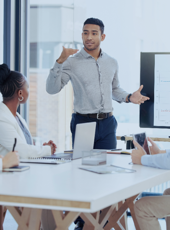 Person standing at the front of a computer speaking to a group of people.