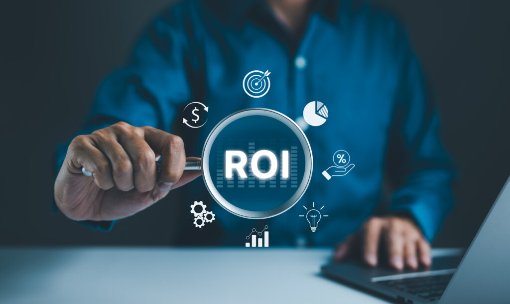 A business professional is seen interacting with a digital ROI (Return on Investment) interface projected over a dark blue background. The interface displays various investment icons such as a dollar sign, target, pie chart, and gears, symbolizing strategic financial planning in technology management.